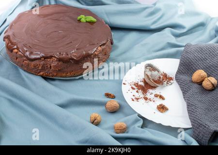 Runder Schokoladenkuchen auf blauem Stoff, Seitenansicht Stockfoto