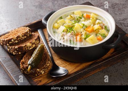 Zupa Ogorkowa Gurkensuppe ist eine traditionelle polnische und litauische Suppe, die aus sauren, gesalzenen Gurken und Wurzelgemüse in der Nähe des Topfes auf dem besteht Stockfoto