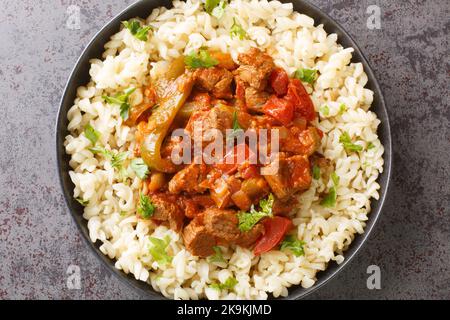 Porkolt ist ungarisch für Rindereintopf, der durch Schmoren von Fleisch und köcheln mit Zwiebeln, Paprika in einer Sauce auf Tomatensauce mit Eiernudeln Nokedli serviert wird Stockfoto