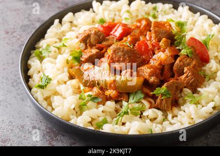 Porkolt ist ungarisch für Rindereintopf, der durch Schmoren von Fleisch und köcheln mit Zwiebeln, Paprika in einer Sauce auf Tomatensauce mit Eiernudeln Nokedli serviert wird Stockfoto