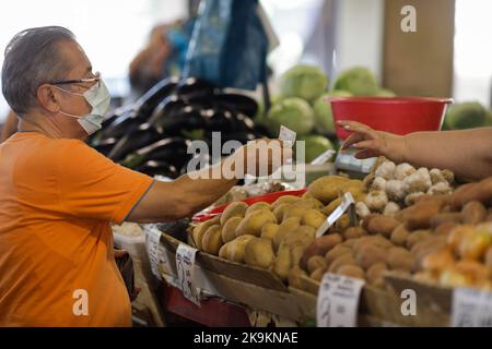 Bukarest, Rumänien - 4. August 2022: Details zur geringen Schärfentiefe (selektiver Fokus) mit einem Mann, der Gemüse von einem Stand auf dem Obor-Markt in Buch kauft Stockfoto