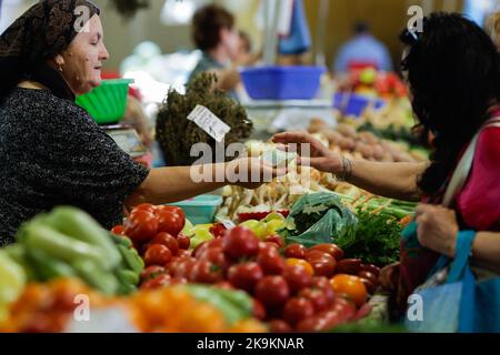 Bukarest, Rumänien - 4. August 2022: Details zur geringen Schärfentiefe (selektiver Fokus) mit einem Mann, der Gemüse von einem Stand auf dem Obor-Markt in Buch kauft Stockfoto
