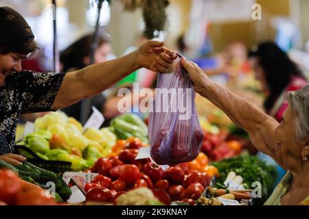 Bukarest, Rumänien - 4. August 2022: Details zur geringen Schärfentiefe (selektiver Fokus) mit einem Mann, der Gemüse von einem Stand auf dem Obor-Markt in Buch kauft Stockfoto