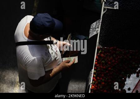 Bukarest, Rumänien - 4. August 2022: Details zur geringen Schärfentiefe (selektiver Fokus) mit einem Mann, der Gemüse von einem Stand auf dem Obor-Markt in Buch kauft Stockfoto