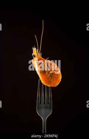 Gedämpfter Garnelendampf auf Gabel isoliert schwarzen Hintergrund Kopieplatz. Isoliert schwarzen Hintergrund Backlight hintergrundbeleuchteten Food-Konzept bereit zu essen Stockfoto