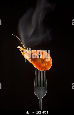 Gedämpfter Garnelendampf auf Gabel isoliert schwarzen Hintergrund Kopieplatz. Isoliert schwarzen Hintergrund Backlight hintergrundbeleuchteten Food-Konzept bereit zu essen Stockfoto