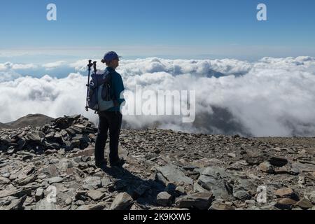 Walker in ihren 60ern genießt den Blick über die Wolken auf dem Gipfel des Puigmal, Katalanisch, Pyrenäen, Spanien Stockfoto