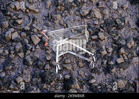 Trolley-Wagen, der am verschmutzten Strand aufgegeben wurde Stockfoto