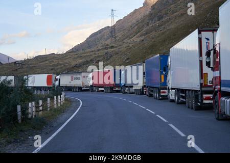 Kazbegi, Georgien - 2. Oktober 2022: Mehrere Kilometer lange LKW-Lkws an der Seite der georgischen Militärautobahn bei Kazbegi warten auf das Kreuz Stockfoto