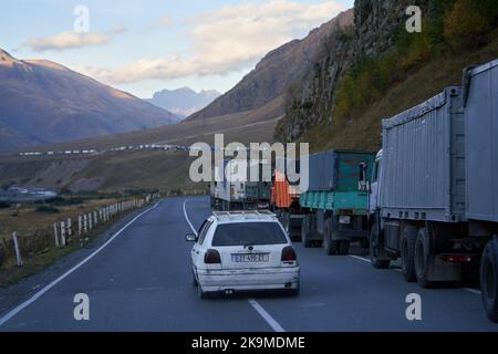 Kazbegi, Georgien - 2. Oktober 2022: Mehrere Kilometer lange LKW-Lkws an der Seite der georgischen Militärautobahn bei Kazbegi warten auf das Kreuz Stockfoto