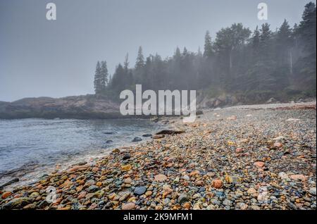 Bunte runde Felsen am Little Hunters Beach im Acadia National Park, Maine. Die Flut kommt, als die Wellen abstürzen. Stockfoto