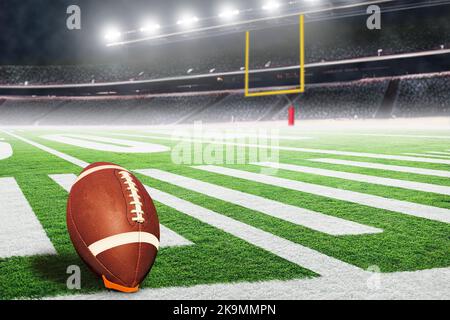 American Football Stadium mit Torpfosten und Ball auf Abschlag bereit für den Spielfeldtreffer. Konzentrieren Sie sich auf den Vordergrundball mit geringer Schärfentiefe im Hintergrund Stockfoto