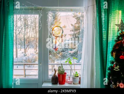 Traumfänger, der in einer gemütlichen Raumeinrichtung am Fenster hängt. Stockfoto