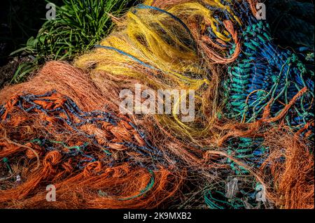 Verworrene, bunte Fischernetze in einem Haufen am Kai. Stockfoto