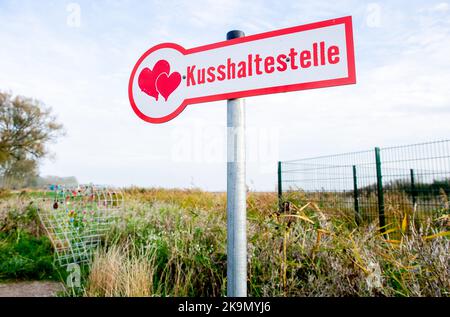 Wangerland, Deutschland. 29. Oktober 2022. Ein Schild mit der Aufschrift 'Kissing stop' steht in einem Feld neben einem Drahtgeflecht, das für sogenannte Liebesschlösser bestimmt ist. In der Nähe des Dorfes Bassens in der Gemeinde Wangerland können Liebhaber in diesem Rastplatz am Straßenrand für einen Kuss und gemeinsame Momente anhalten und sich mit einem von ihnen mitgebrachten Liebesschloss verewigen. Quelle: Hauke-Christian Dittrich/dpa/Alamy Live News Stockfoto