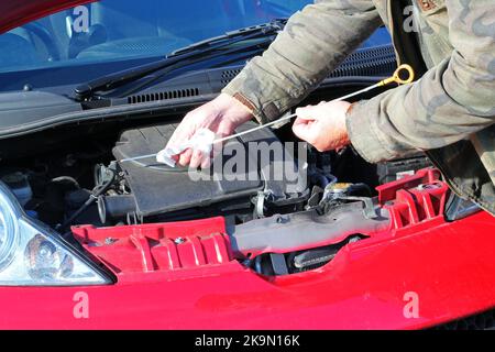 Mann, der den Ölstand in seinem Auto oder Fahrzeug überprüft. Ölmess-Stab prüfen, um die Markierung zu sehen. Stockfoto