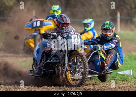 Purleigh Barns Farm, Latchingdon, Essex, Großbritannien. 29. Oktober 2022. Solo- und Seitenwagen-Motorräder sowie Quad-Bikes fuhren in verschiedenen Klassen auf einem Feld in der Nähe von Maldon in Essex um eine schlammige ovale Rennstrecke, organisiert vom Southend & District Motorcycle Club. Grasstrack-Rennen ist ähnlich wie Speedway-Rennen. Die Wettkampfklassen variieren zwischen im Uhrzeigersinn und gegen den Uhrzeigersinn. Die Motorleistung reicht bis zu 1000cc und umfasst Vintage-Maschinen vor 1975. 124 - Danny Hill und Harry Hill in der linken Seitenwagenklasse Stockfoto