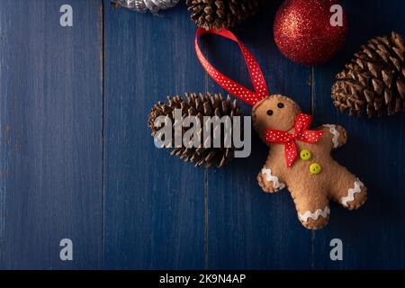 Lebkuchenmann filzte Figur mit Tannenzapfen und roten weihnachtskugeln zur weihnachtsdekoration auf vintage blauem Holz Hintergrund. Speicherplatz für Ihren kopieren Stockfoto