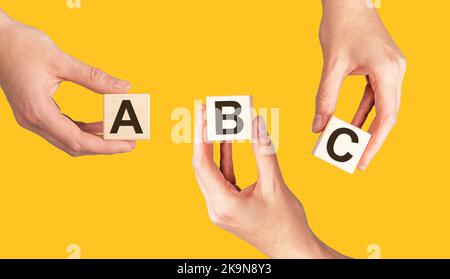 ABC-Buchstaben auf Würfeln in den Händen auf dem Hintergrund. Hochwertige Fotos Stockfoto