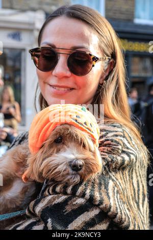 London, Großbritannien. 29. Oktober 2022. Eine Teilnehmerin mit ihrem Hund im Kürbishut. Die Columbia Road feiert die mexikanische Tradition mit dem Londoner Day of the Dead Festival mit Kostümen, Künstlern, einer Parade, dekorierten Geschäften und Ständen. Kredit: Imageplotter/Alamy Live Nachrichten Stockfoto