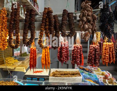 Georgische Süßigkeiten an der Theke. Feigenbündel. Nüsse in gefrorenem Traubensaft auf der Theke. Pflaume churchkhela auf dem Markt. Süße Speisen im Sortiment. Stockfoto