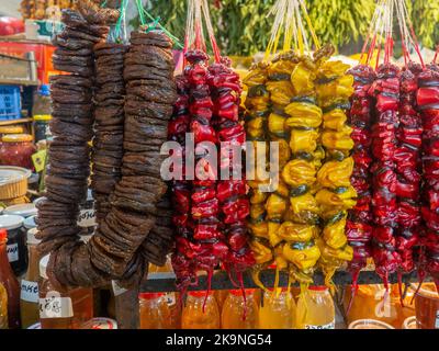 Georgische Süßigkeiten an der Theke. Feigenbündel. Nüsse in gefrorenem Traubensaft auf der Theke. Pflaume churchkhela auf dem Markt. Süße Speisen im Sortiment. Stockfoto