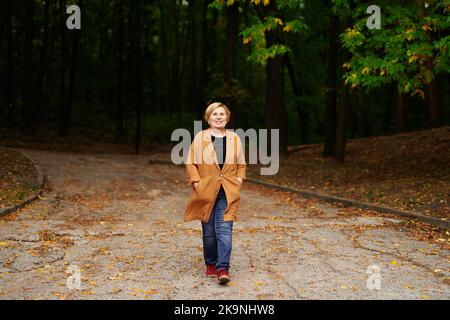 Porträt einer attraktiven kaukasischen Rentnerin, die in der Fallsaison im öffentlichen Park spazieren geht. Lächelnd glücklich ältere Menschen genießen die Natur, Freiheit Urlaub reisen. Hochwertige Fotos Stockfoto