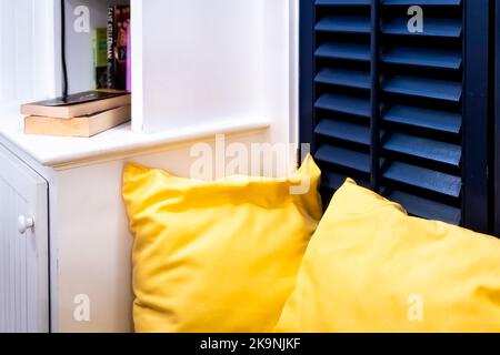 Fenstersitzsofa Sofa durch Fensterläden und Bücherregal Schränke mit Büchern in modernem Haushausdesign Inneneinrichtung Nahaufnahme Stockfoto