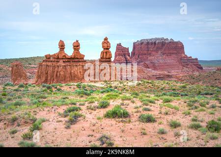 Hoodoo orange Farbe Felsen Sandstein einzigartige Formationen im Goblin Valley State Park, Utah mit Wüstenpflanzen Vegetation durch roten Sand, blauen Himmel Stockfoto