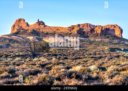 Rock auf einer Klippe im Arches Nationalpark in Utah Butte anzeigen Während der morgendlichen Sonnenaufgang mit orange Farbe ausgeglichen Stockfoto