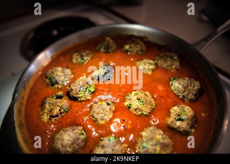 Makro-Nahaufnahme von hausgemachten italienischen Fleischbällchen Kochen in der Bratpfanne mit roter Tomatensauce in der heimischen Küche Stockfoto