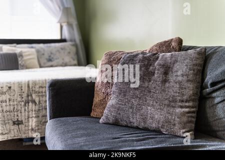 Schlafzimmer-Studio-Zimmer mit Lampen, Kissen auf dem Bett und Sofa-Couch im modernen Motel-Zimmer mit weißen Vorhängen und grün gestrichenen Wänden Stockfoto