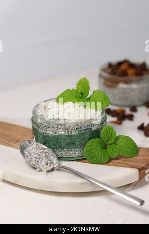 Köstlicher veganer Kokos-Chia-Pudding mit Spirulina und Minze, auf weißem Tisch Stockfoto