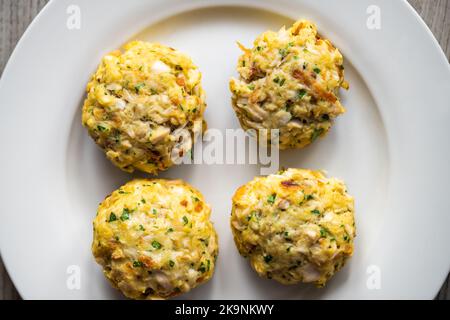 Makro-Nahaufnahme flache Lay Top-Ansicht von gekochten gebratenen Krabben Krabbenfleisch Fischkuchen auf weißem Teller auf Küche Holztisch Stockfoto