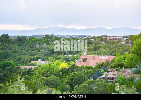 Blick auf die Stadt in Santa Fe, New Mexico Sangre de Cristo Berge durch Wohnstraßenanlage, Grünpflanzen im Sommer und traditionelle lehmhäuser Stockfoto