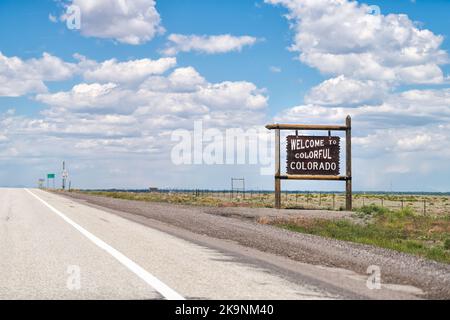 Willkommen zum farbenfrohen Colorado Holzschild von der Autobahn 285 mit staatlicher Grenzlinie durch New Mexico im Sommer in der Stadt Antonito Stockfoto