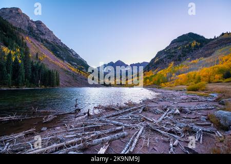 Kastanienbrauner Bells See bei Sonnenaufgang Sonnenlicht in Aspen, Colorado mit Elch Rocky Berggipfel im Schnee im Herbst farbenfroher Herbst mit lebhaften Bäumen Laub Stockfoto