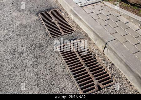 Langes Kanalgitter auf grauem Asphalt aus nächster Nähe Stockfoto