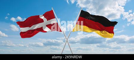 Zwei gekreuzte Flaggen Bundesrepublik Deutschland und Dänemark winken im Wind bei bewölktem Himmel. Konzept der Beziehung, Dialog, Reisen zwischen zwei Gräfin Stockfoto