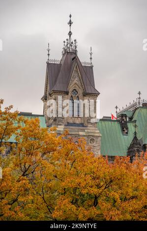 Die Türme des East Blocks auf dem kanadischen Parlamentshügel, die sich in der Ferne über den Bäumen des Rideau-Kanals erheben. Stockfoto