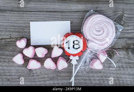 Glückwunschkarte zum 18.. Geburtstag und pinke Marschwalben liegen auf einem Holzbrett Stockfoto