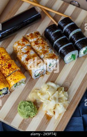 Sushi-Set mit verschiedenen Arten von Brötchen und Sashimi aus Aal, Lachs, Thunfisch, Garnelen, rotem Kaviar und fliegendem Fischrogen aus Tobiko. Pan-asiatische und asiatische Fo Stockfoto