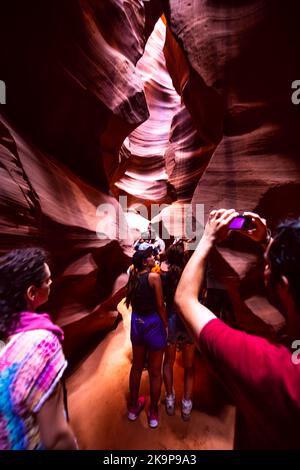 Page, USA - 10. August 2019: Tour einer Gruppe von Menschen im Upper Antelope Slot Canyon, Arizona, die Fotos mit dem Telefon von Sandsteinfelsen machen Stockfoto