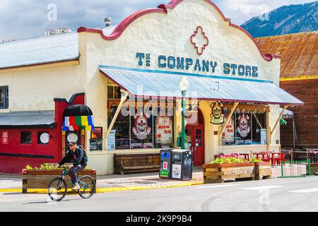 Crested Butte, USA - 21. Juni 2019: Colorado Town Street mit Pizzeria Restaurant Cafe Store Shop in der Innenstadt im Sommer, Mann Menschen Fahrrad fahren Stockfoto