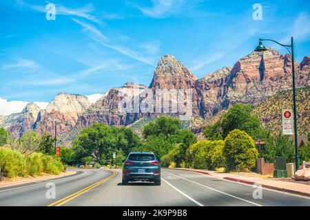 Springdale, USA - 5. August 2019: Bergschluchtstadt am Zion Nationalpark mit Autos auf der Hauptstraße mit Schluchten im Hintergrund im Sommer Stockfoto