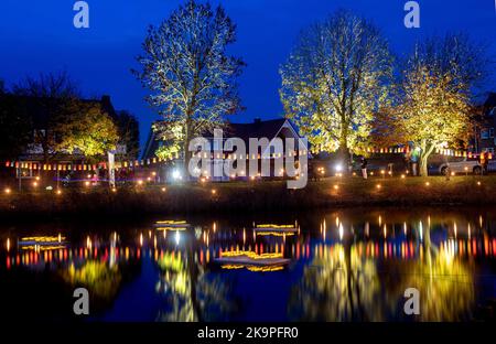 Horumersiel, Deutschland. 29. Oktober 2022. Zahlreiche bunte Laternen hängen an einer Linie um den natürlichen See Kolk im Stadtzentrum und spiegeln sich im Wasser. Hunderte von Laternen und Fackeln sowie schwebende Lichter in bunten Seerosen verwandeln den Kolk während der traditionellen Kolk-Beleuchtung in ein buntes Lichtermeer. Quelle: Hauke-Christian Dittrich/dpa/Alamy Live News Stockfoto