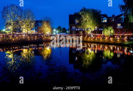 Horumersiel, Deutschland. 29. Oktober 2022. Zahlreiche bunte Laternen hängen an einer Linie um den natürlichen See Kolk im Stadtzentrum und spiegeln sich im Wasser. Hunderte von Laternen und Fackeln sowie schwebende Lichter in bunten Seerosen verwandeln den Kolk während der traditionellen Kolk-Beleuchtung in ein buntes Lichtermeer. Quelle: Hauke-Christian Dittrich/dpa/Alamy Live News Stockfoto