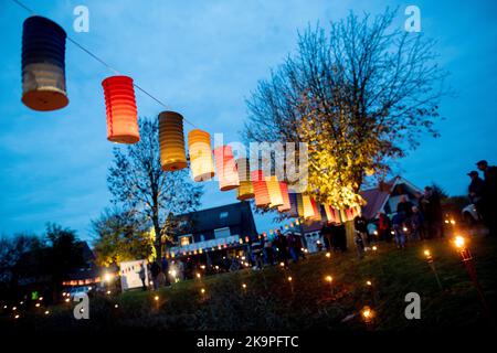 Horumersiel, Deutschland. 29. Oktober 2022. Zahlreiche bunte Laternen hängen an einer Linie rund um den Natursee Kolk im Stadtzentrum. Hunderte von Laternen und Fackeln sowie schwebende Lichter in bunten Seerosen verwandeln den Kolk während der traditionellen Kolk-Beleuchtung in ein buntes Lichtermeer. Quelle: Hauke-Christian Dittrich/dpa/Alamy Live News Stockfoto