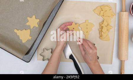 Weihnachts-Shortbread-Kekse mit Himbeermarmelade Rezept, close up Backprozess, flach legen. Koch macht Löcher in der Plätzchenmitte mit einem Stroh Stockfoto