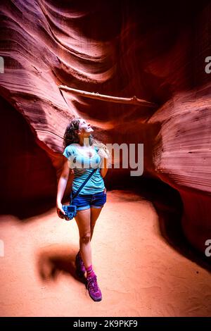 Junge Frau, die im Sommer in der Wüstenlandschaft des Upper Antelope Canyon mit Sandstein-Felsformationen steht Stockfoto